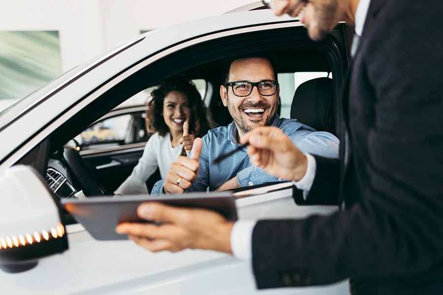 Carsalesman working with young couple